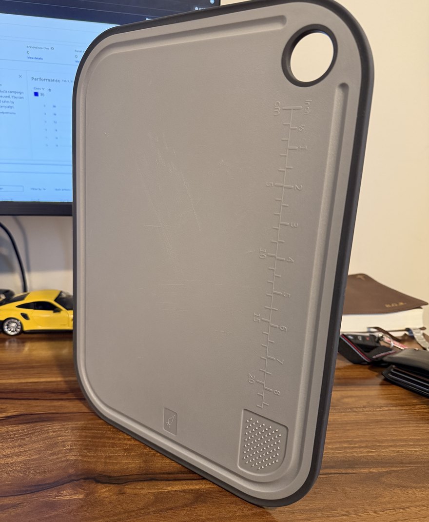 Phone photo of a grey cutting board leaning against a desk.
